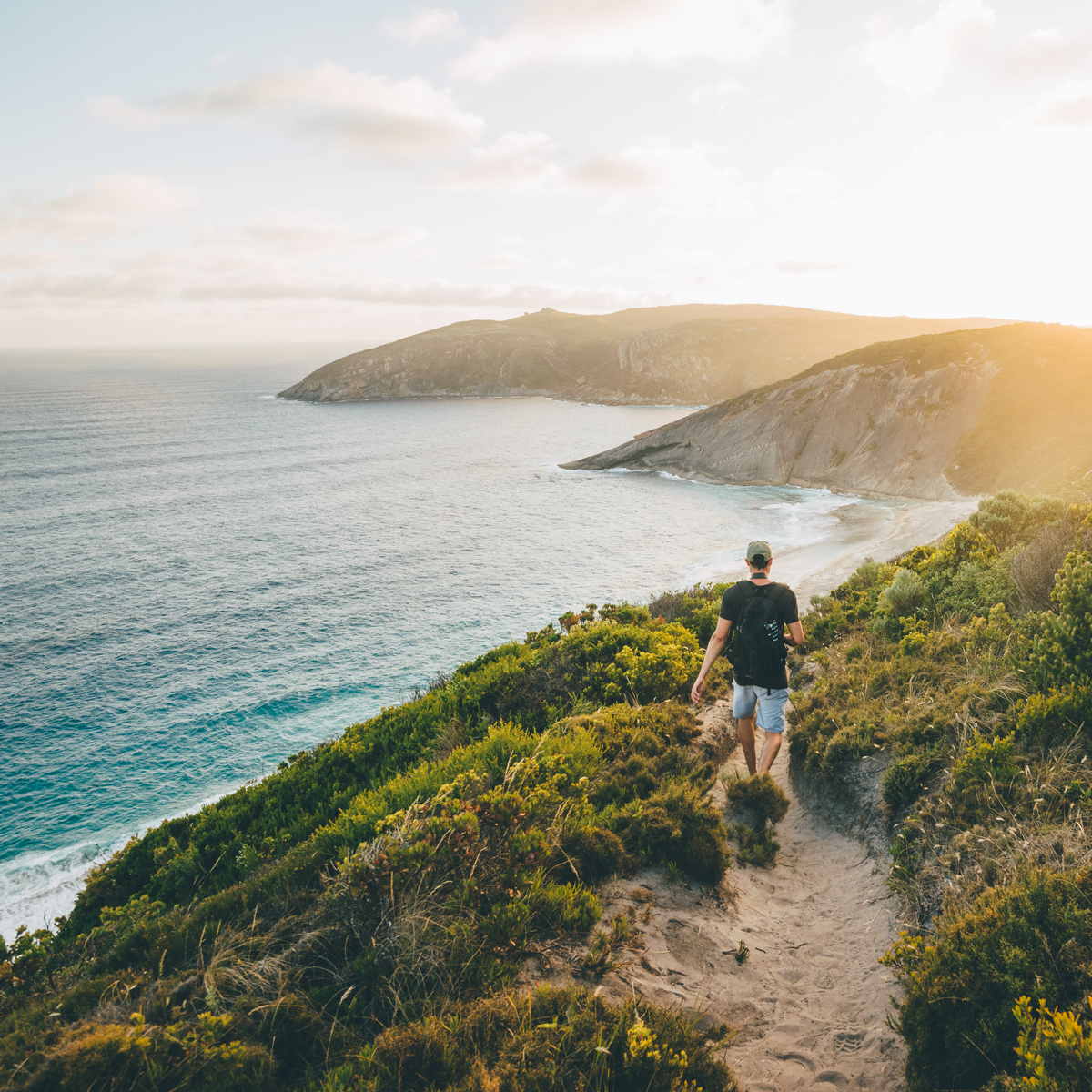 Mann geht bei einem Sonnenuntergang am Great Ocean Road spazieren.